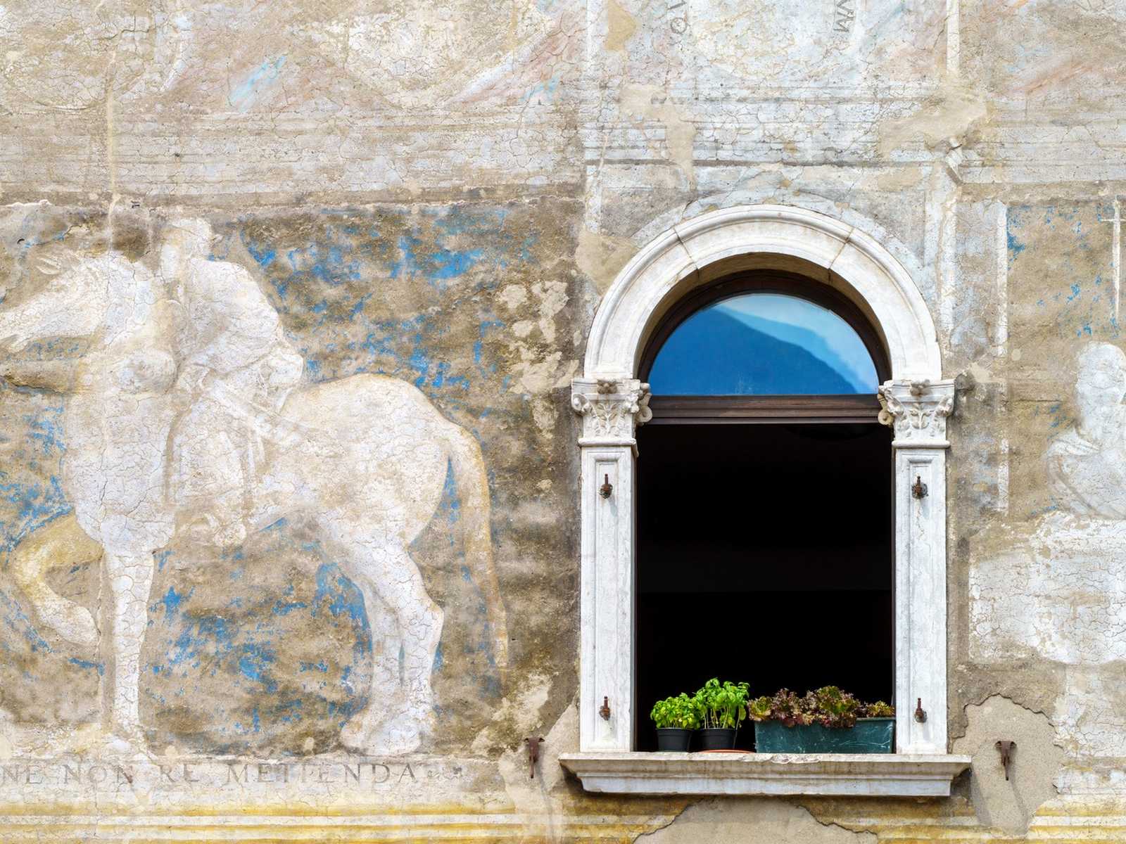 טרנטו (Trento) – חלון אבן מקושט על חזית מצוירת במרכז ההיסטורי