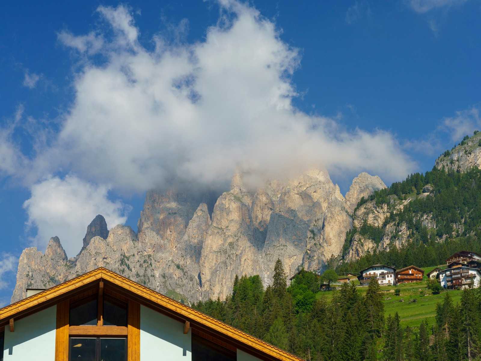 בתי עץ אלפיניים על רקע מצוקי הדולומיטים במוענה (Moena)