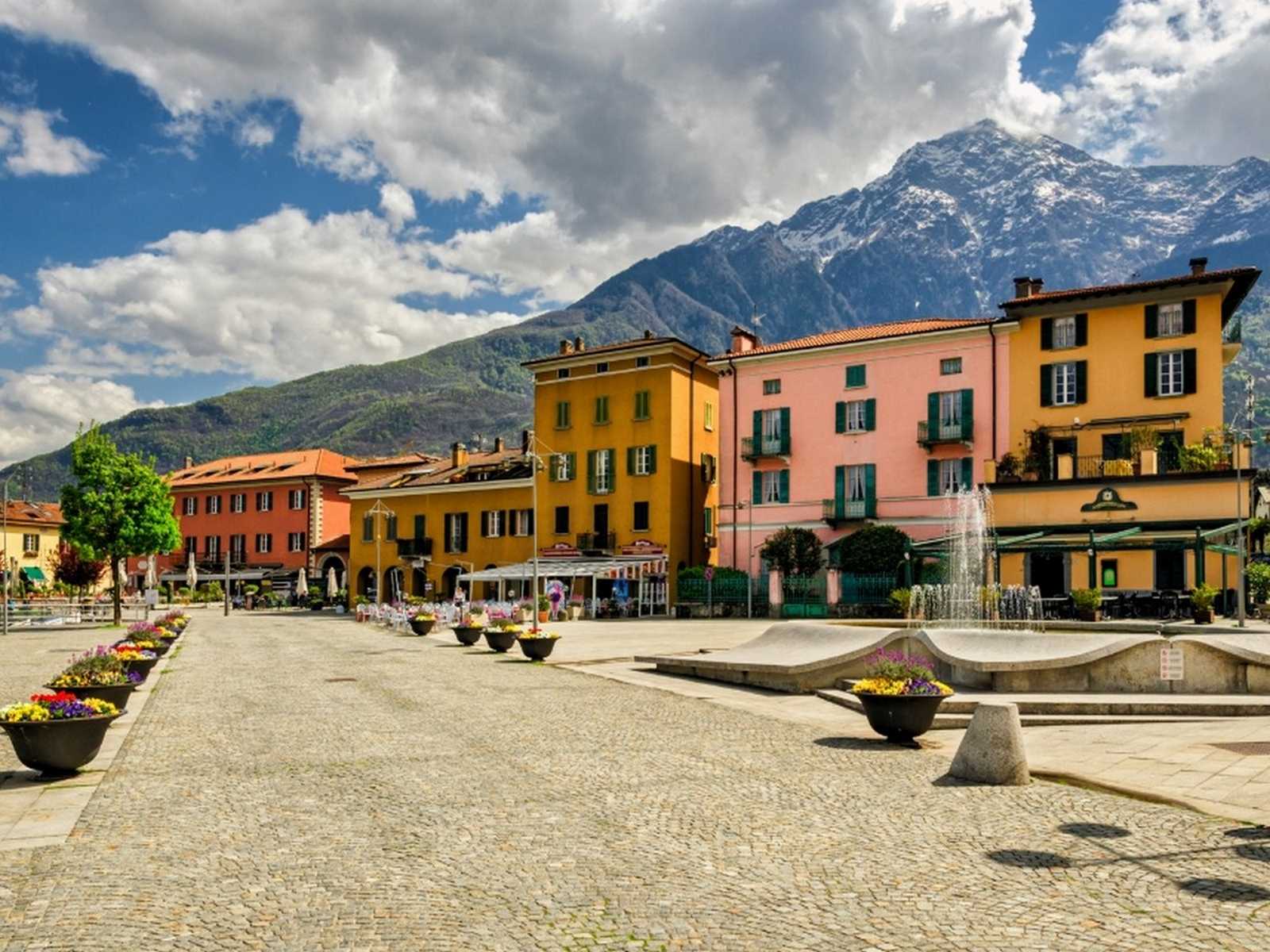 מסלול הליכה בגרין ווי בכיכר ציורית עם בתים צבעוניים והרים ברקע