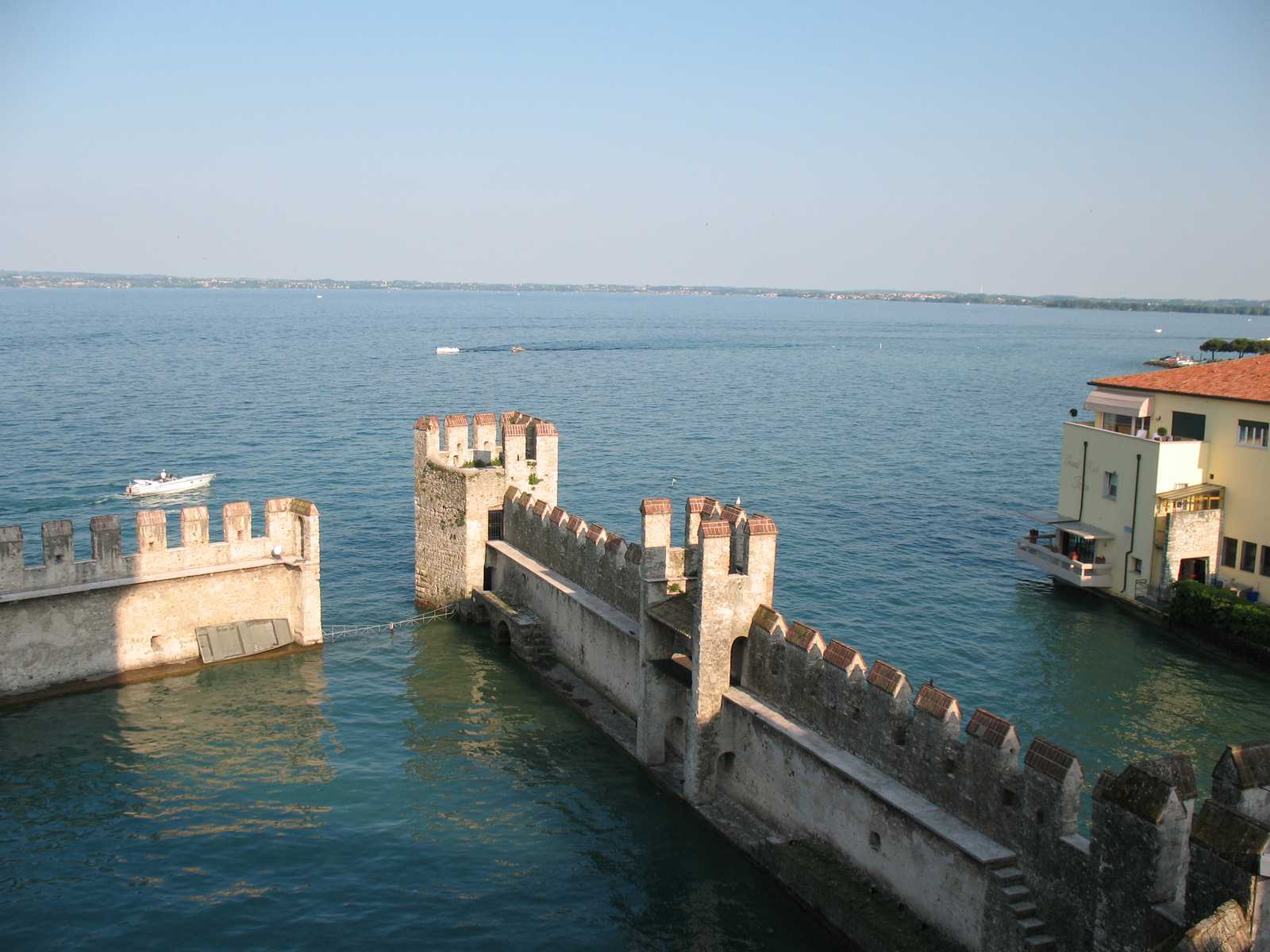 החומה והכניסה לטירת סירמיונה מעל המים הצלולים של אגם גארדה