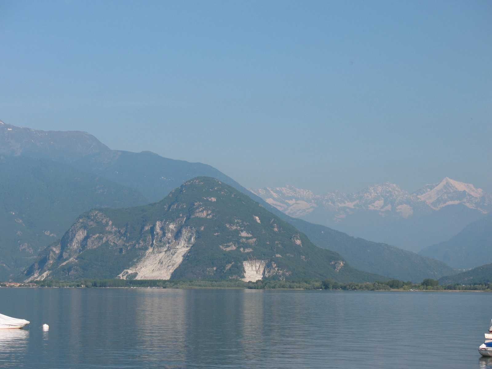 נוף רחב של אגם קומו עם הרים מרשימים המשתקפים במים השקטים ואווירה רגועה של צפון איטליה