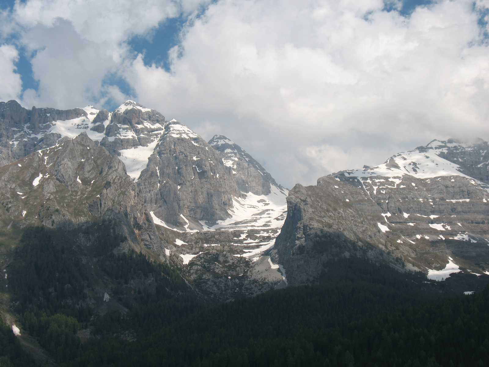 פסגות סלעיות גבוהות של דולומיטים מכוסות שלג תחת שמיים מעוננים.