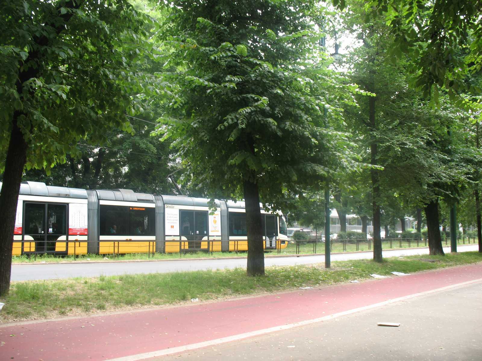 חשמלית מודרנית נוסעת לאורך שדרה ירוקה בעיר מילאנו.