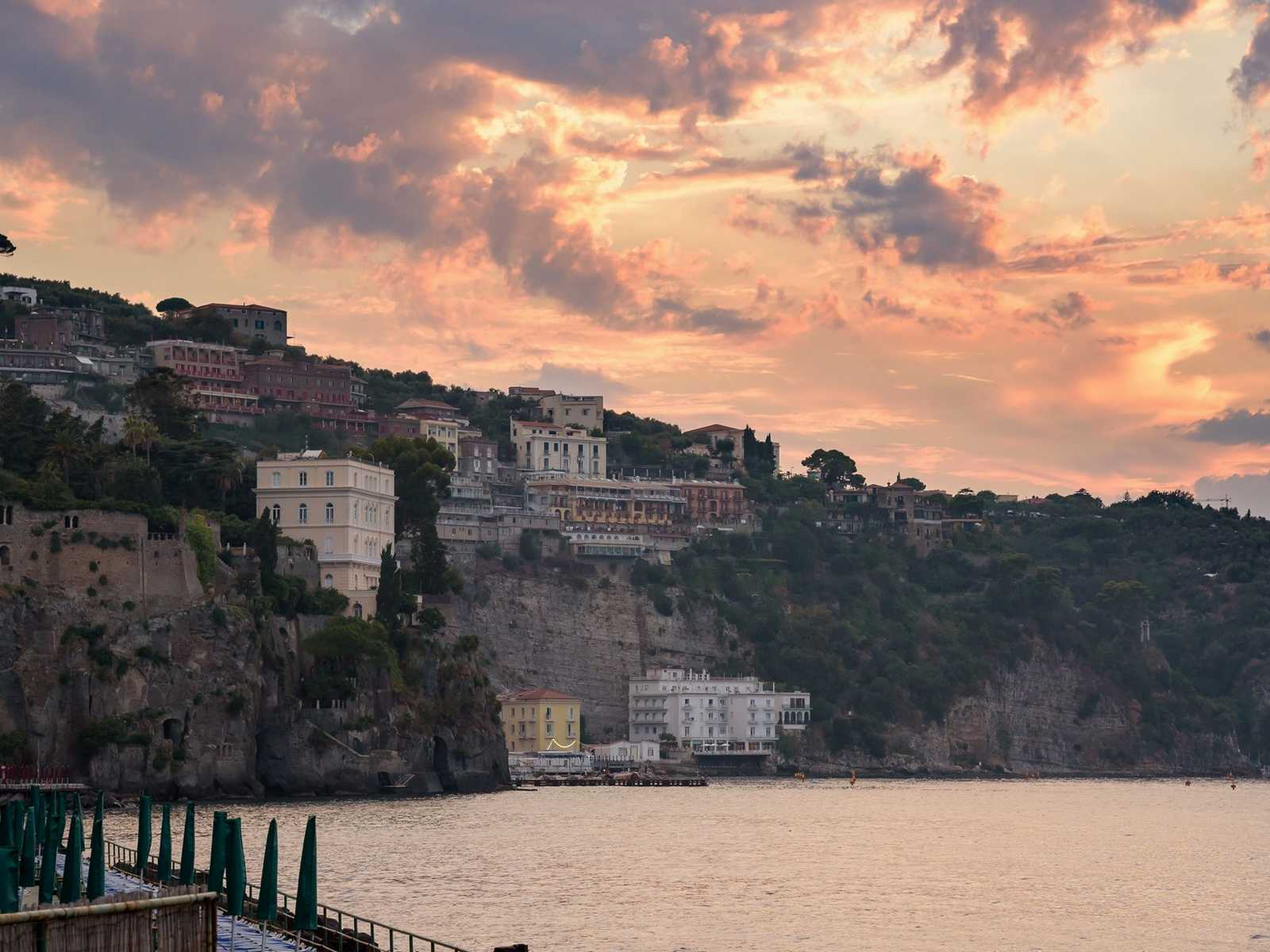 נוף שקיעה מעל הצוקים והבתים הצבעוניים של סורנטו על מפרץ נאפולי