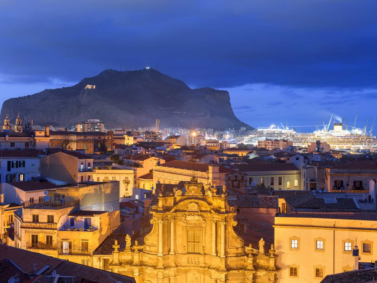 נוף ערב של עיר סיציליאנית עם הר אתנה ברקע ב־סיציליה בדצמבר