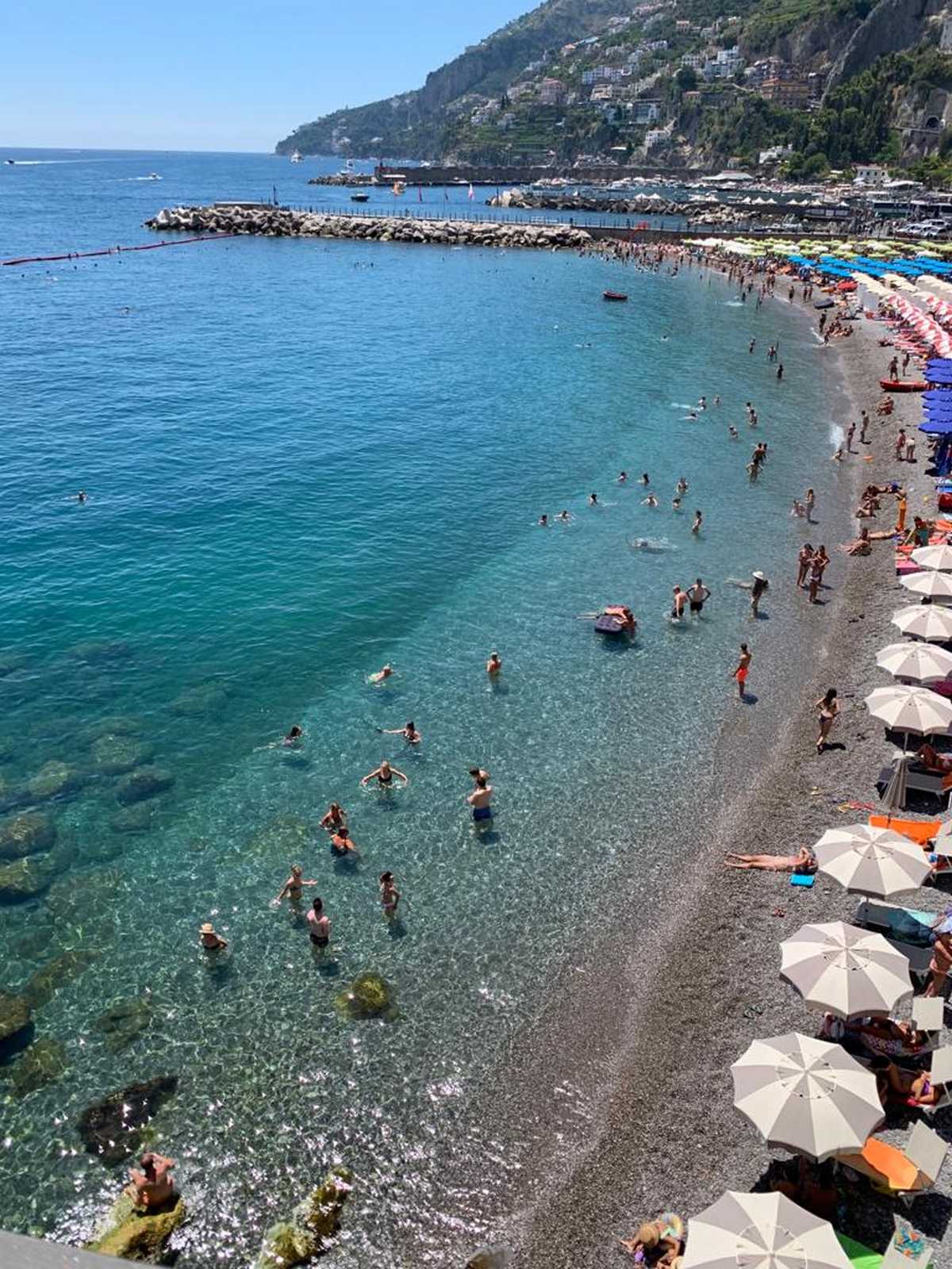 חוף ים פופולרי עם מים טורקיז ואנשים נופשים בקמפניה